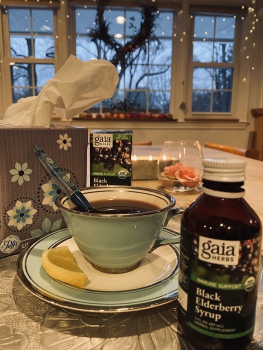 Black Elderberry Syrup on table next to tea cup